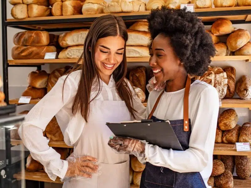 Women in a bakery smiling looking at a clipboard