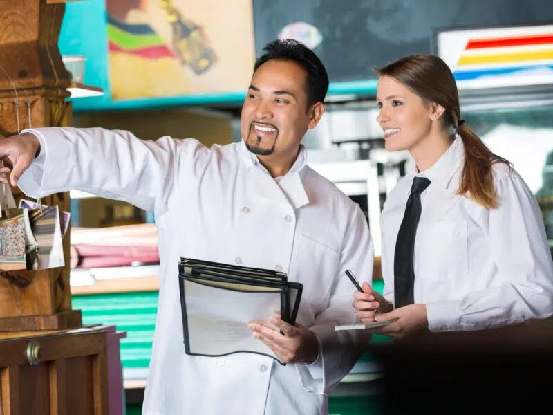 Chef pointing and woman making notes