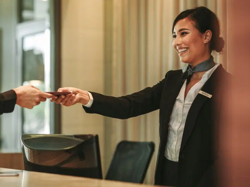 hotel front desk worker taking credit card from customer