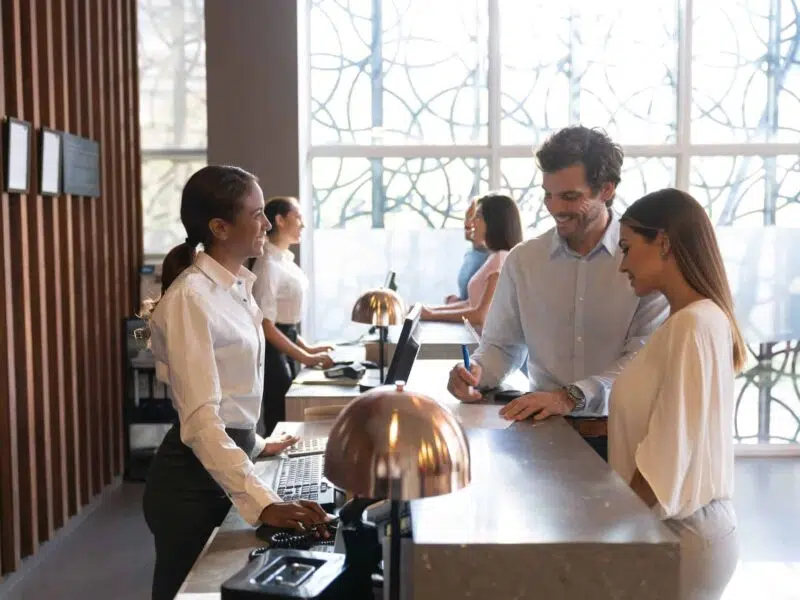 Couple signing in at a hotel reception desk.