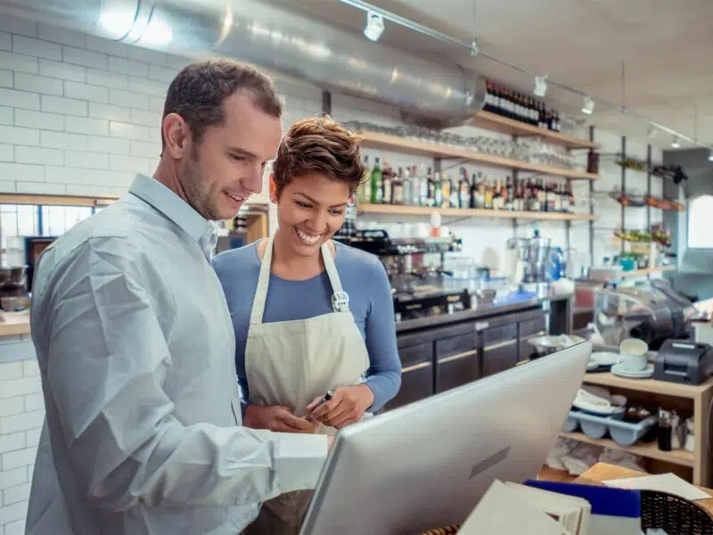 Man and woman in a bar kitchen looking at a monitor