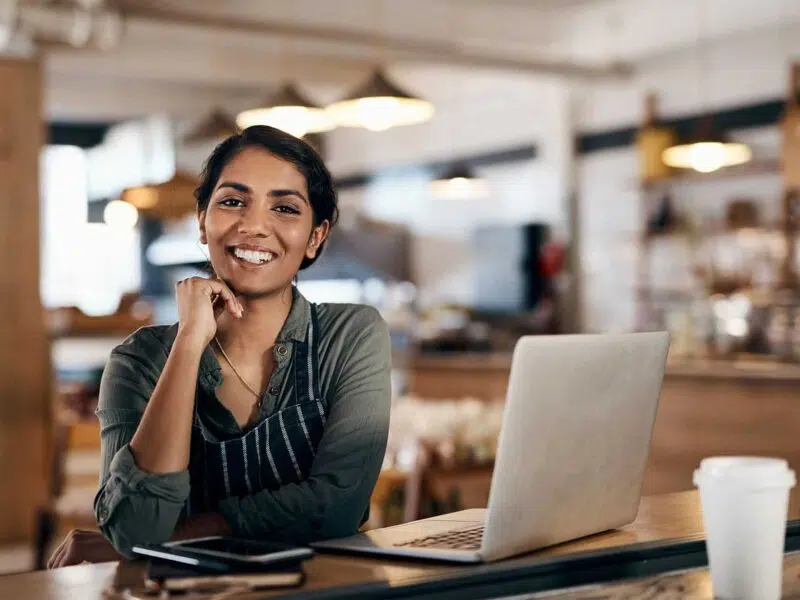 Woman smiling using inventory management software on a laptop
